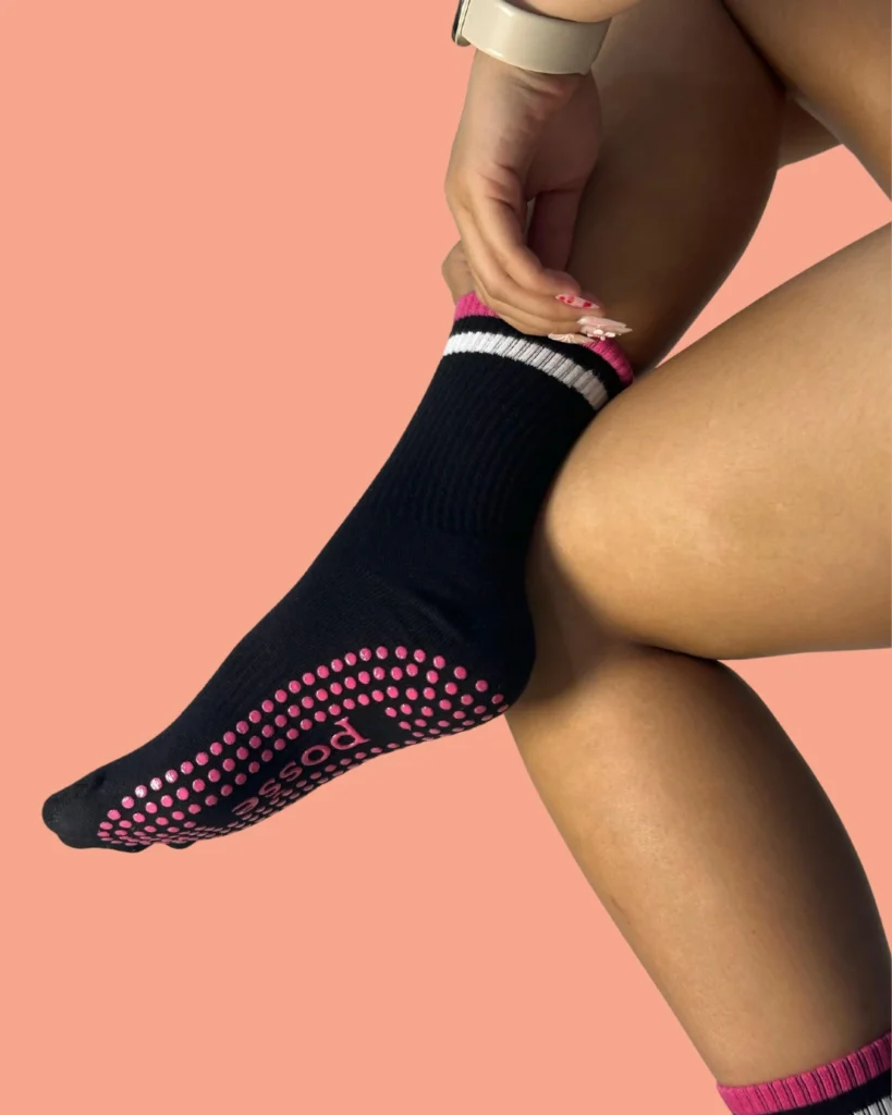 Posše black No Chill grip socks with pink silicone soles, worn on crossed legs with peach background